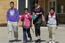 FILE - In this March 16, 2011 file photo, Heather Coffy, right center, leaves the St. Monica School with her children, left to right, Delano Coffy, 15, Alanna Marshall, 8, and Darius Coffy, 11, in Indianapolis. Students like Delano are at the heart of brewing political fights and court battles over whether public dollars should go to school vouchers to help make private schools more affordable. (AP Photo/Michael Conroy, File)