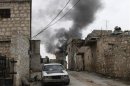 Smoke rises behind a car decorated with an Islamist flag in Aleppo