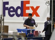 Handlers scan and affix a courier route label onto packages moving down the belt at the Marina Del Rey, California FedEx station December 12, 2011. REUTERS/Fred Prouser