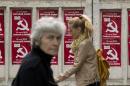 FILE - In this May 28, 2015, file photo, people walk by posters advertising the Party of Communists of Moldova, in Chisinau, Moldova. Moldovans are voting in local elections Sunday, June 14, 2015, which are seen as a test of whether the country is committed to European integration or will move closer to Russia's orbit. (AP Photo/Vadim Ghirda, File)