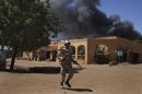 A Malian soldier runs past smoke from a petrol station on fire during fighting with Islamists in Gao