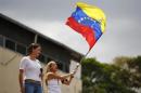 Opposition deputy Maria Corina Machado watches as   Lilian Tintori (R), wife of jailed opposition leader Leopoldo Lopez, wave a   Venezuelan flag during a protest in Caracas February 26, 2014. REUTERS/Jorge   Silva