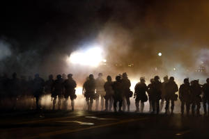Police walk through a cloud of smoke and tear gas as &hellip;