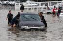 Iraqi youngsters help push a vehicle through flood waters in the capital Baghdad, on November 11, 2013, following overnight rains