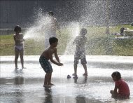 Varios niños se refrescan bajo el agua de una fuente en el parque Madrid Río para protegerse de las altas temperaturas. EFE/Archivo