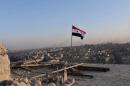 A Syrian national flag flutters near a general view of eastern Aleppo after Syrian government soldiers took control of al-Sakhour neigbourhood in Aleppo