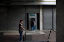 Women withdraw money from an ATM outside a National Bank branch in Athens