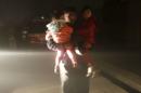 A man carries his children to a safe area from the site of an explosion in Kabul, Afghanistan