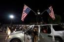 A protester holds upside down American flags on top of a car outside the police department in Ferguson