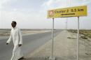 A man walks past a sign for "Lukoil" in al-Toraba area near oilfield of West Qurna-2 in Basra