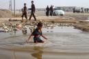 A displaced Iraqi boy from the Fallujah area plays in a puddle of water at a camp near Amiriyiah al-Fallujah on June 22, 2016