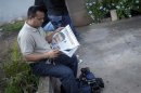 A journalist reads a local paper with a photograph of fellow journalist Alfredo Villatoro outside a funeral home where a wake for Villatoro was taking place in Tegucigalpa
