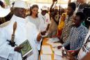 Gambian President Jammeh holds a copy of the Quran while speaking to a poll worker at a polling station during the presidential election in Banjul