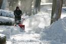 A man clears a sidewalk using a snowblower in the Bronx on January 3, 2014 in New York