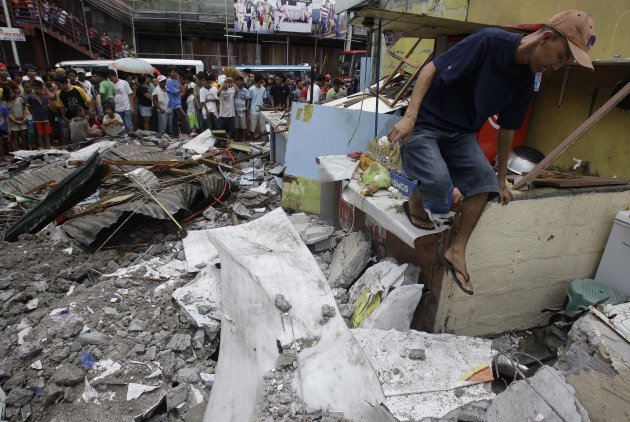 A man walks along the rubble of a collapsed wall as it was knocked down by strong winds, killing one man and injuring two others in suburban Novaliches, Quezon City, Philippines, Sunday, Aug. 28, 2011