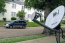 In this May 11, 2009 photo, a mini-van passes a DirecTV satellite dish in a residential area adjoining downtown Jackson, Miss. Tribune Broadcasting says there's been no settlement with DirecTV Inc. in their contract negotiations, which means DirecTV subscribers in 19 U.S. markets will lose access to certain programming, Saturday, March 31, 2012. (AP Photo/Rogelio V. Solis)