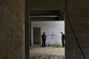 FILE - In this Thursday, July 3, 2014, file photo, state police stand inside a warehouse where a black cross covers a wall near blood stains on the ground, after a shootout between Mexican soldiers and alleged criminals on the outskirts of the village of San Pedro Limon, in Mexico state, Mexico. The New York-based group Human Rights Watch is calling on Aug. 22, 2014, on the Mexican government to fully investigate a supposed shootout in which soldiers killed 22 suspects while suffering only one soldier wounded. (AP Photo/Rebecca Blackwell, File)
