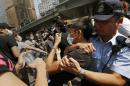 A police officer tries to stop a man who removing the metal barricades that protesters have set up to block off main roads near the heart of the city's financial district. Hong Kong Monday, Oct. 13, 2014. An angry crowd tried to charge barricades used by pro-democracy protesters to occupy part of downtown Hong Kong as a standoff with authorities dragged into a third week. (AP Photo/Vincent Yu)