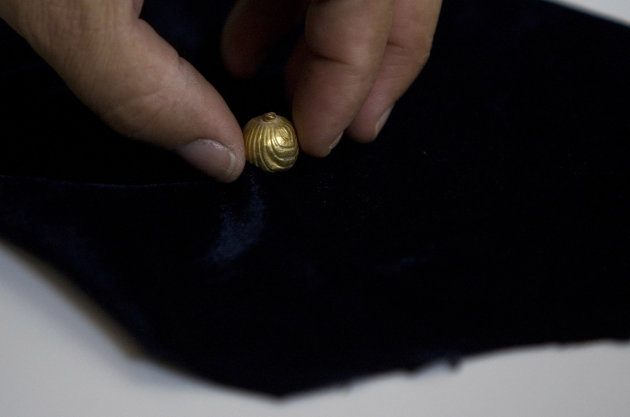A worker for the IAA, Israel's Antiquities Authority holds a gold bell found in Jerusalem, Sunday, July 24, 2011. The tiny golden bell preserved for two millennia underneath Jerusalem is ringing again