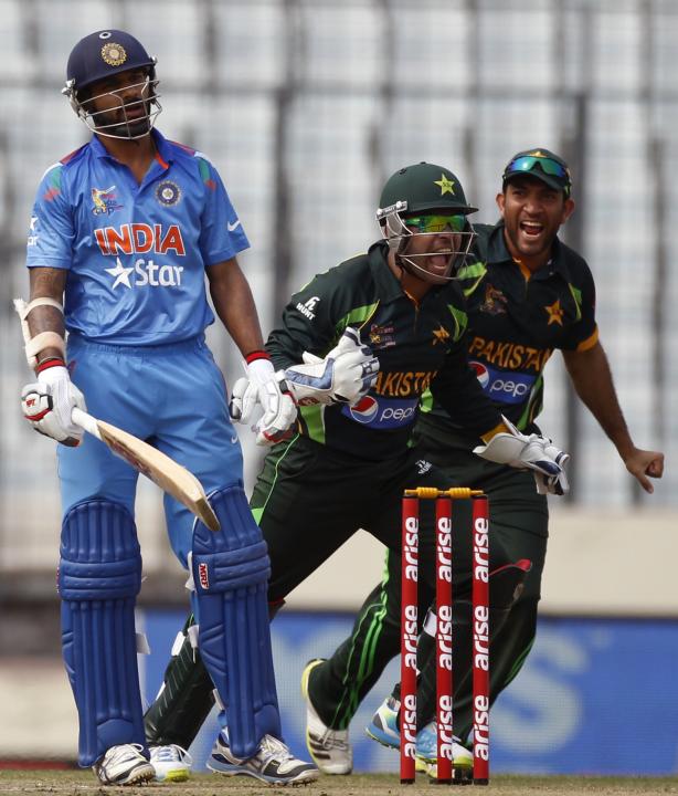 India&#39;s Dhawan reacts as Pakistan&#39;s wicketkeeper Akmal and Maqsood celebrate his dismissal during their ODI cricket match in Asia Cup 2014 in Dhaka.
