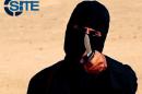A masked, black-clad militant brandishes a knife in this still image from video