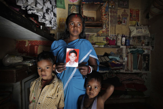 In this Monday, March 25, 2013, photo, Pinky Devi shows the picture of her son Ravi Shankar, who disappeared three years ago, as she stands with her sons, Rahul, 7, left, and Ramesh, 5, in their one room tenement, in New Delhi, India. Ravi is among the more than 90,000 children who go missing in India each year. More than 34,000 of them are never found, the government said last year. (AP Photo / Manish Swarup)