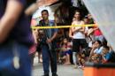 Member of the Philippine National Police (PNP) stands guard while residents look on near the scene where two suspected drug pushers were killed during a police operation, in metro Manila