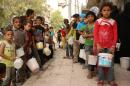 Syrian children, who were displaced from their houses due to the ongoing conflict in Syria, queue up to receive aid food in the rebel side of the northern city of Aleppo, on September 7, 2015