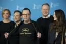 Director Lars von Trier, centre, reveals a tee shirt which has the Cannes film festival symbol and the slogan Persona Non Grata underneath as he poses for photographers at the photo call for the film Nymphomaniac at the International Film Festival Berlinale in Berlin, Sunday, Feb. 9, 2014. In 2011 Von Trier was asked to leave the Cannes film festival after a bizarre, rambling news conference in which he said he sympathizes with Adolf Hitler. (AP Photo/Axel Schmidt)