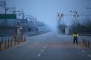 A South Korean police officer stands guard on an empty road connecting the Kaesong Industrial Complex (KIC) inside the North Korean border with the South's CIQ in Paju