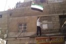 An anti-government protester waves a flag during the funeral of Sukaria, whom protesters said was killed by forces loyal to Assad, in Damascus