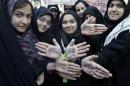 In this picture taken on Friday, Nov. 2, 2012, Iranian school girls show their hands with writing in Persian in support supreme leader Ayatollah Ali Khamenei, denouncing the U.S. and one of them with word "Nuclear Scientist" in an annual state-backed rally in front of the former U.S. Embassy in Tehran, Iran, commemorating 33rd anniversary of the embassy takeover by militant students. On Nov. 4, 1979, students who believed the embassy was a center of plots against Iran held 52 Americans hostages for 444 days, and the US severed formal diplomatic ties in response. In a sharp counterpoint to the Western outreach by President Hassan Rouhani's government, hard-line factions in Iran have amplified their bluster and backlash in messages that they cannot be ignored in any diplomatic moves with Washington either in the nuclear talks or beyond. (AP Photo/Vahid Salemi)