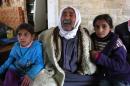 Mehrez Humeidan, 70, who is visually impaired, sits between his granddaughters Ikram, 8, left, and Inaam, 10, right, inside a restaurant after they fled into the eastern Lebanese border town of Arsal, Lebanon, Monday, Nov. 18, 2013. Thousands of Syrians have fled to Lebanon over the past days as government forces attack the western town of Qarah near the border with Lebanon. (AP Photo/Bilal Hussein)