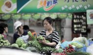 Chinesa escolhe legumes e verduras em um mercado de Pequim, em junho de 2011
