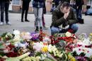 A man reacts next to flowers for the shooting victims outside the "Kruttoende" cultural centre in Copenhagen on February 15, 2015