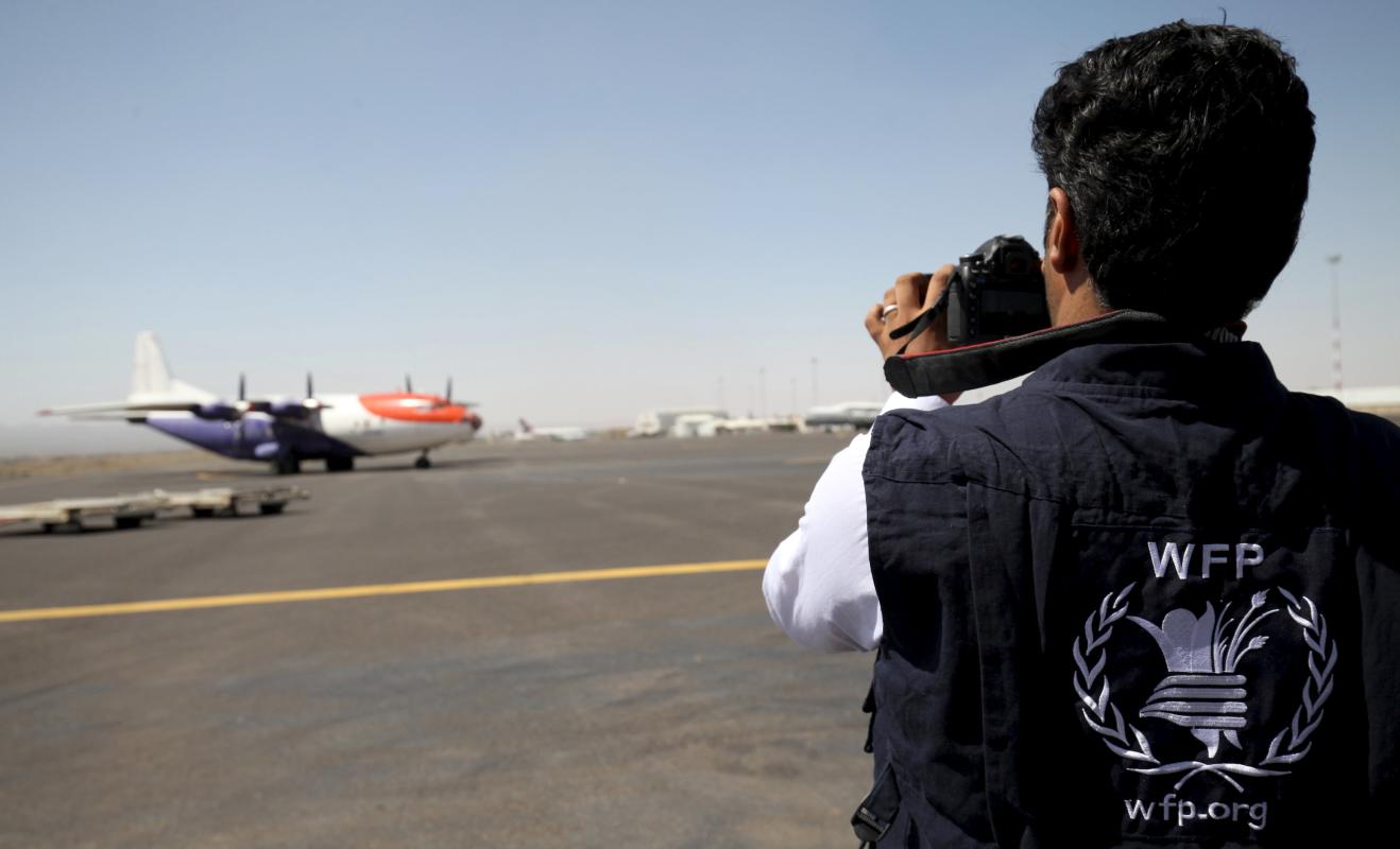 A WFP employee takes pictures of a plane carrying aid from the World Food Organization at Sanaa International Airport