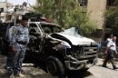 Security forces inspect the scene of a car bomb attack in the commercial area of Karradah in Baghdad, Iraq, Thursday, May 30, 2013. Iraqi officials say a series of morning bomb explosions in Iraq killed dozens in the latest eruption of violence rattling the country. (AP Photo/ Hadi Mizban)