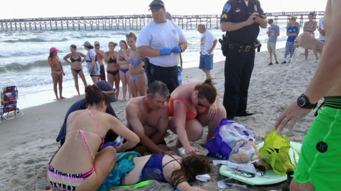 Emergency responders assist a teenage girl at the scene of a shark attack in Oak Island, N.C., Sunday, June 14, 2015. Mayor Betty Wallace of Oak Island, a seaside town bordered to the south by the Atlantic Ocean, said that hours after the teenage girl suffered severe injuries in a shark attack Sunday a teenage boy was also severely injured. (Steve Bouser/The Pilot, Southern Pines, N.C. via AP) MANDATORY CREDIT