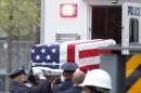 A flag-draped casket is lifted out of a police vehicle during the ceremonial transfer of unidentified remains of those killed at the World Trade Center from the Office of the Chief Medical Examiner to the World Trade Center site, Saturday, May 10, 2014, in New York. The remains will be transferred to an underground repository in the same building as the National September 11 Memorial Museum. (AP Photo/Jason DeCrow)