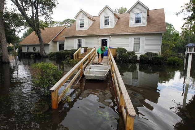 Lechelle Spalding pulls a boat up to her flooded home after a storm surge on the Outer Banks in Kitty Hawk, N.C., Sunday, Aug. 28, 2011 in the aftermath of Hurricane Irene after it left the North Caro