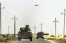 A helicopter flies overhead as soldiers in military vehicles proceed towards al-Jura district in El-Arish city