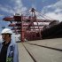Employee stands next to container ship at Ningbo port