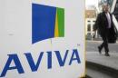 A man walks past an AVIVA logo outside the company's head office in the city of London