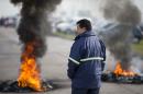 A worker stands next to burning tires outside the entrance of RR Donnelley printing plant in the outskirts of Buenos Aires, Argentina, Monday, Aug. 11, 2014. RR Donnelley, a Fortune 500 company from Chicago, closed its plant in Argentina without warning catching its 400 workers by surprise when they showed up for work Monday morning. The company posted a letter outside it's entrance announcing its closing due to "unsolvable crisis." (AP Photo/Victor R. Caivano)