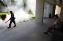 A resident shields his nose as pest control officer carry out fogging in the Aljunied Crescent cluster in Singapore