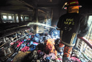 A firefighter douses the inside of a garment factory outside Dhaka, Bangladesh, Sunday, Nov. 25, 2012. At least 112 people were killed in a late Saturday night fire that raced through the multi-story garment factory just outside of Bangladesh's capital, an official said Sunday. (AP Photo/   khurshed
 Rinku)