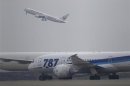 A Japan Airlines aircraft takes off as All Nippon Airways' Boeing Co's 787 Dreamliner plane parks on the tarmac at Haneda Airport in Tokyo