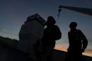 Amsa, 16 years-old, last name not available, a migrant from Somalia, right, watches the sunset as he leaves aboard a ferry the Sicilian Island of Lampedusa, Monday, Oct. 7, 2013. Italian divers recovered 17 more bodies Monday from a smugglers' boat that capsized and sank to bottom of the Mediterranean Sea with hundreds of migrants on board. That brought the confirmed death toll from Thursday's tragedy to 211 before poor weather off the southern island of Lampedusa again halted the recovery operation. Only 155 people of the estimated 500 on board survived the sinking. Scores of bodies are believed to be still trapped in the hull of the 18-meter (59-foot) boat, which is resting 47 meters (154 feet) below the surface. Monday was the first day that divers entered the hull. Coast Guard Capt. Filippo Marini estimated it would take two more days to complete the search and recovery mission. (AP Photo/Luca Bruno)