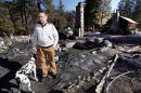 FILE - In this Friday, Feb. 15, 2013 file photo, Rick Heltebrake, with his dog Suni, looks over the burned-out cabin where Christopher Dorner's remains were found after a police standoff Tuesday near Big Bear, Calif. Dorner took his pickup during his escape attempt. Heltebrake, a ranger who takes care of a Boy Scout camp, was checking the perimeter of the camp for anything out of the ordinary when he saw Dorner emerge from behind some trees. (AP Photo/Nick Ut, FIle)