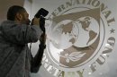 A photographer takes pictures through a glass carrying the International Monetary Fund logo during a news conference in Bucharest